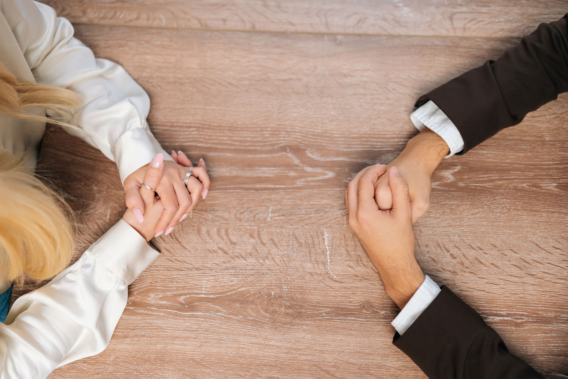 Closeup top view of clasped female and male hands negotiate at table. Concept confrontation, negotiators conflict, employees struggle for leadership at work